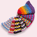 A stack of crochet pride bucket hats on plain background