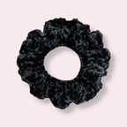 Black crochet scrunchie on plain background