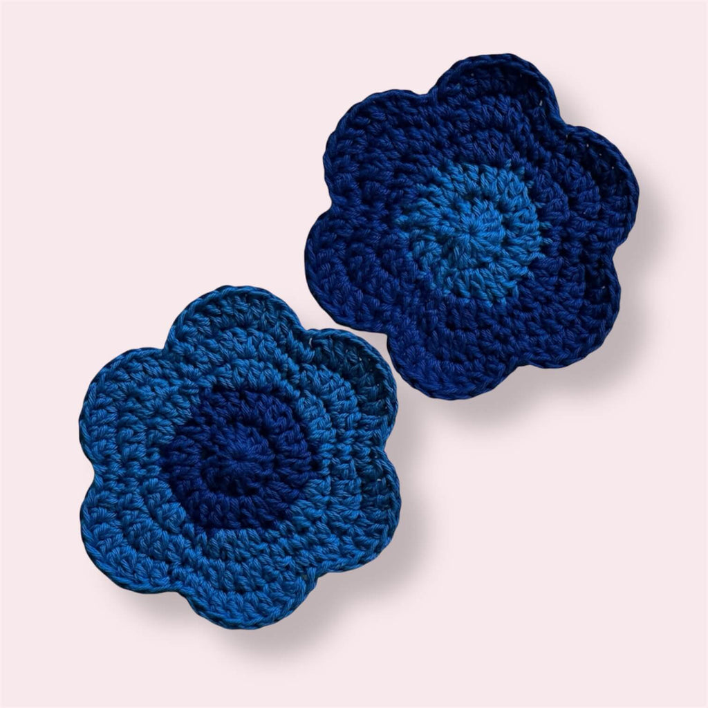 Blue flower-shaped crocheted coasters on plain background
