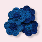 Blue flowershaped crocheted coasters arranged on plain background