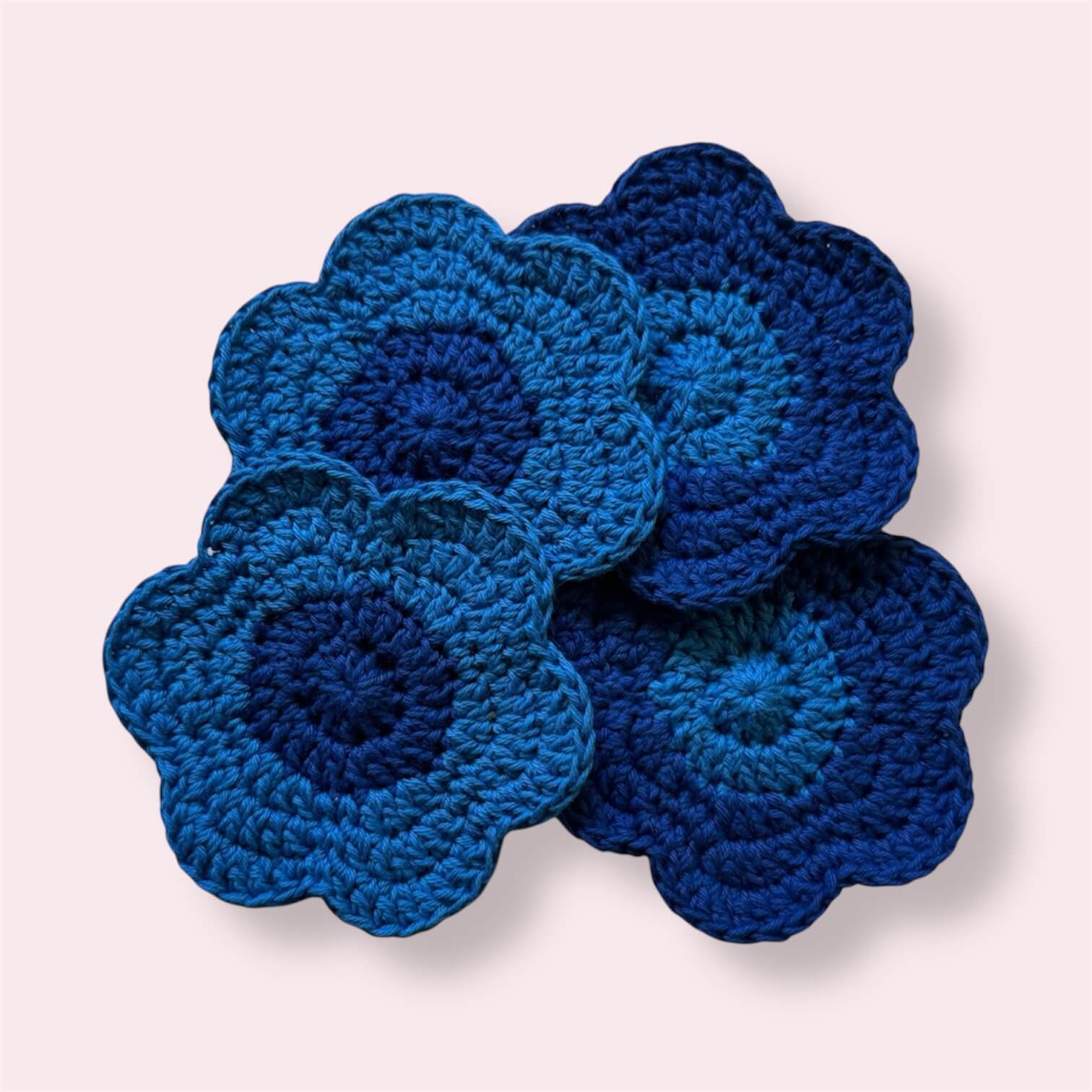 Blue flowershaped crocheted coasters arranged on plain background