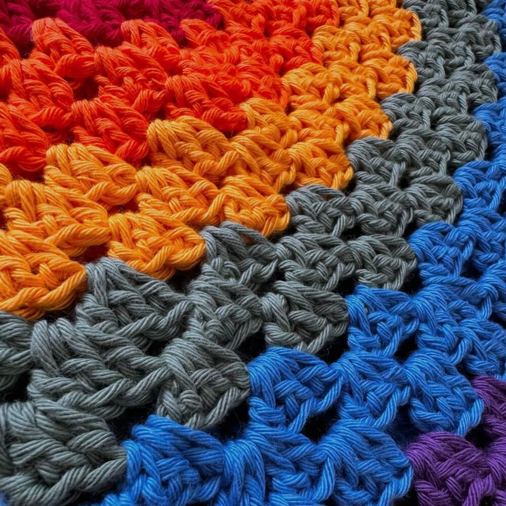 Close-up of a pride crochet bucket hat with red, orange, yellow, green, blue, and purple yarn.
