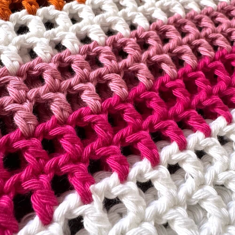 Close-up of crocheted lesbian pride bag with pink, white, and orange colors