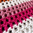 Close-up of crocheted lesbian pride bag with pink, white, and orange colors