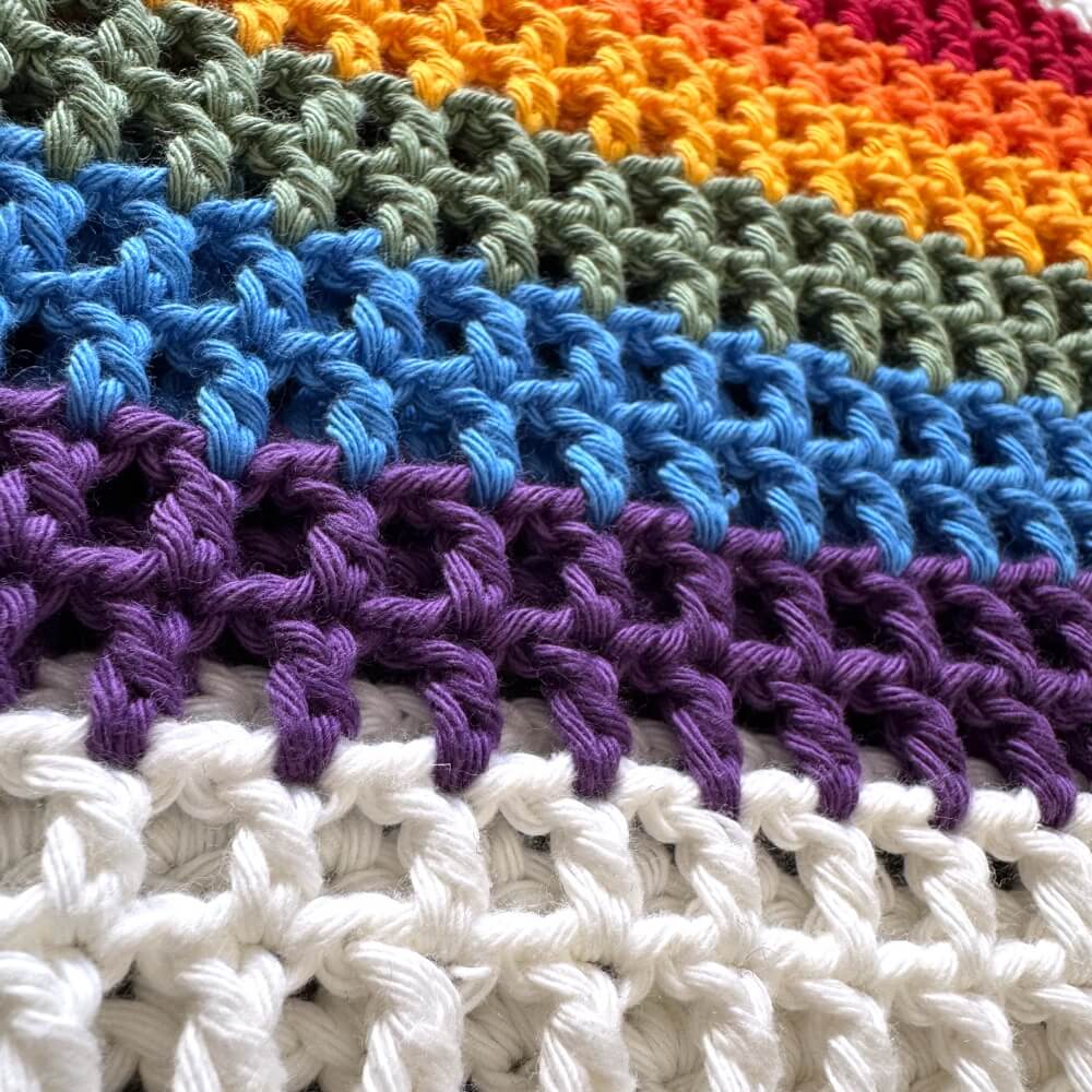 Close-up of crocheted pride bag with white and rainbow colors