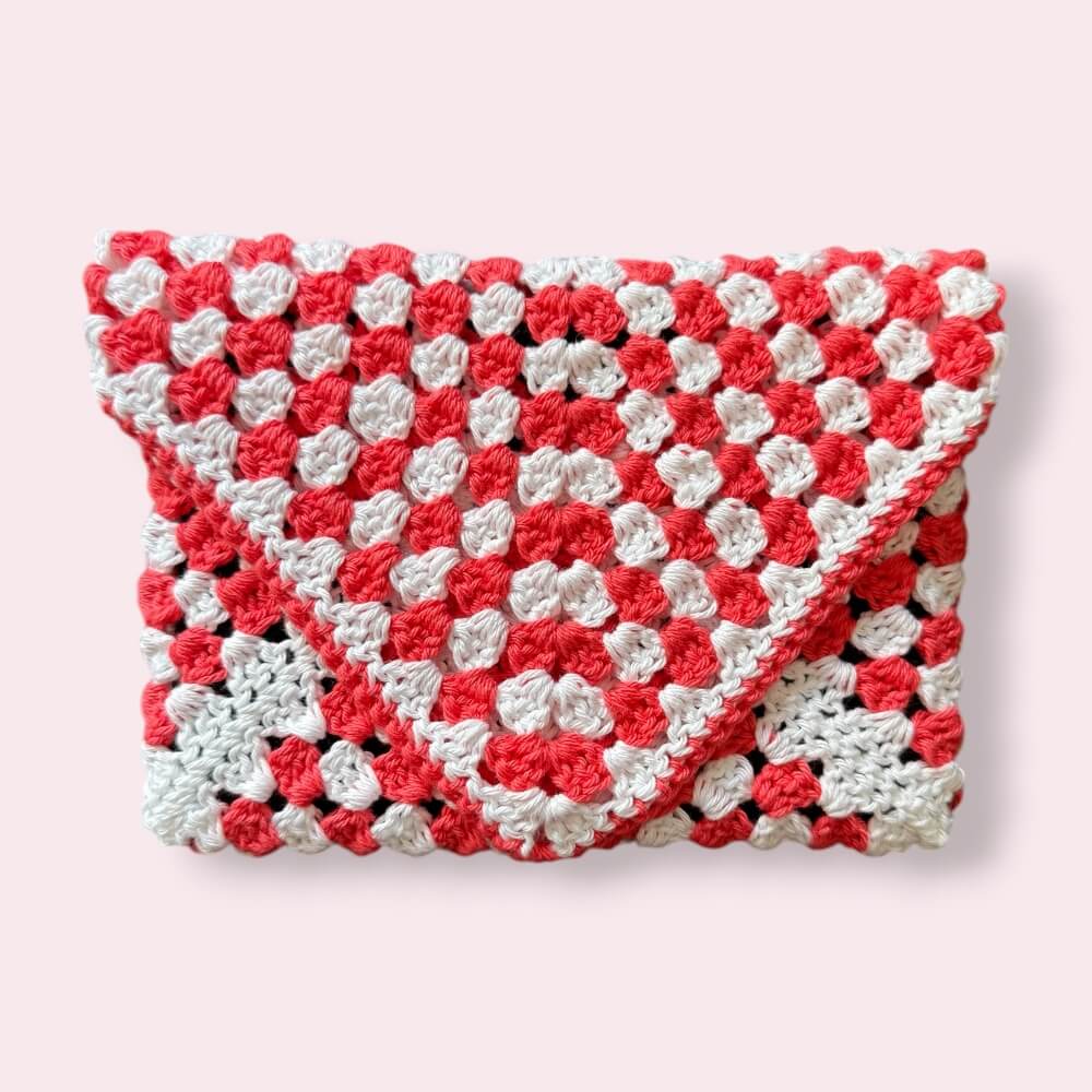 Closed crocheted coral and white kindle sleeve on plain background