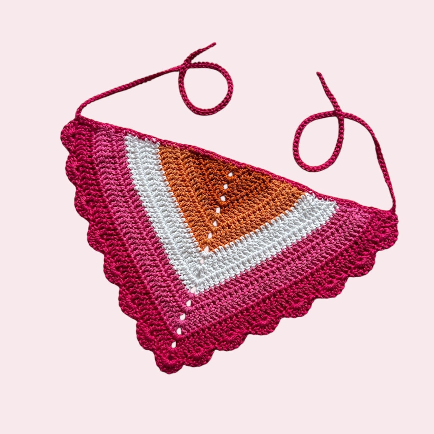 Crochet bandana in lesbian pride colors on a pink background