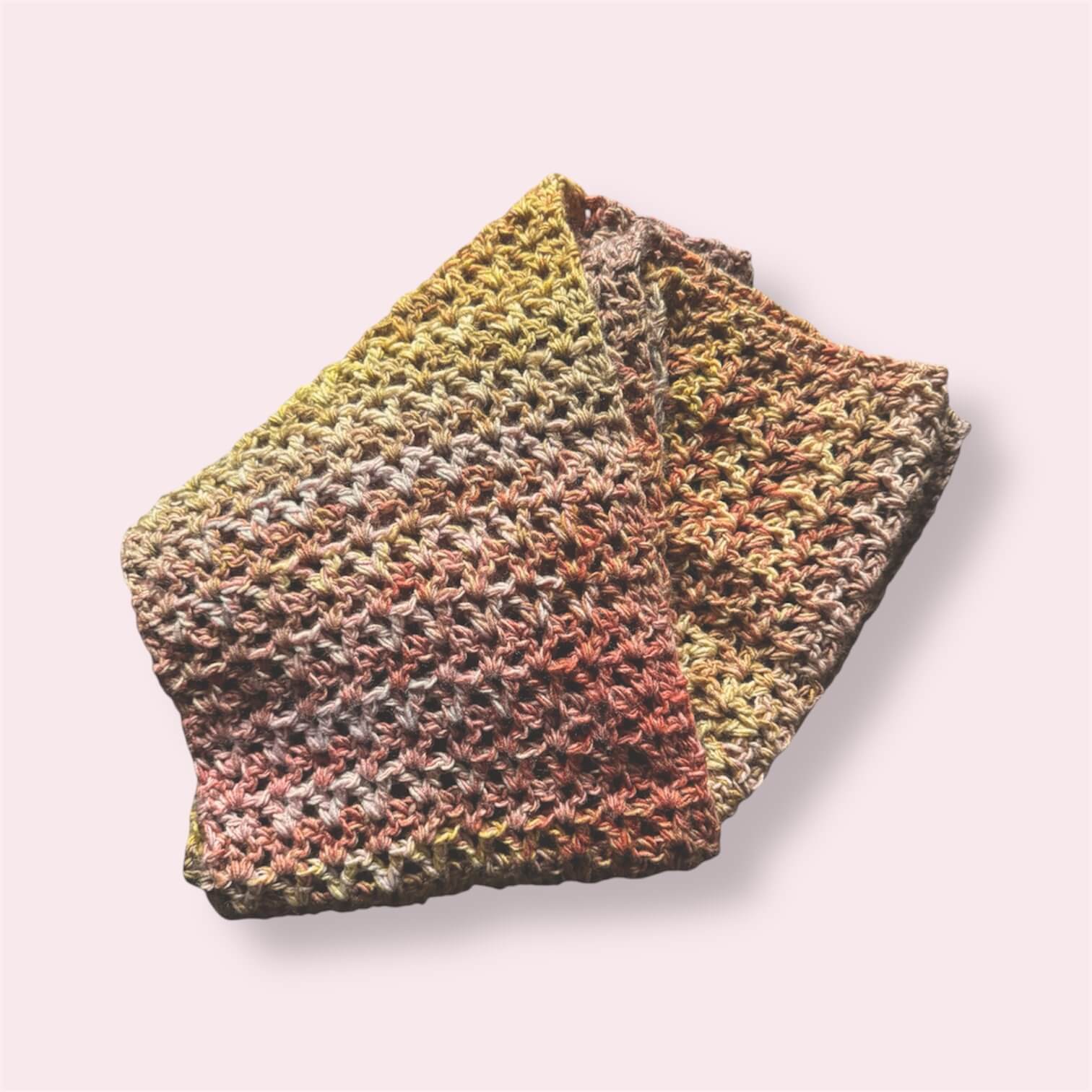 Crocheted scarf in yellow pink and orange colors on plain background