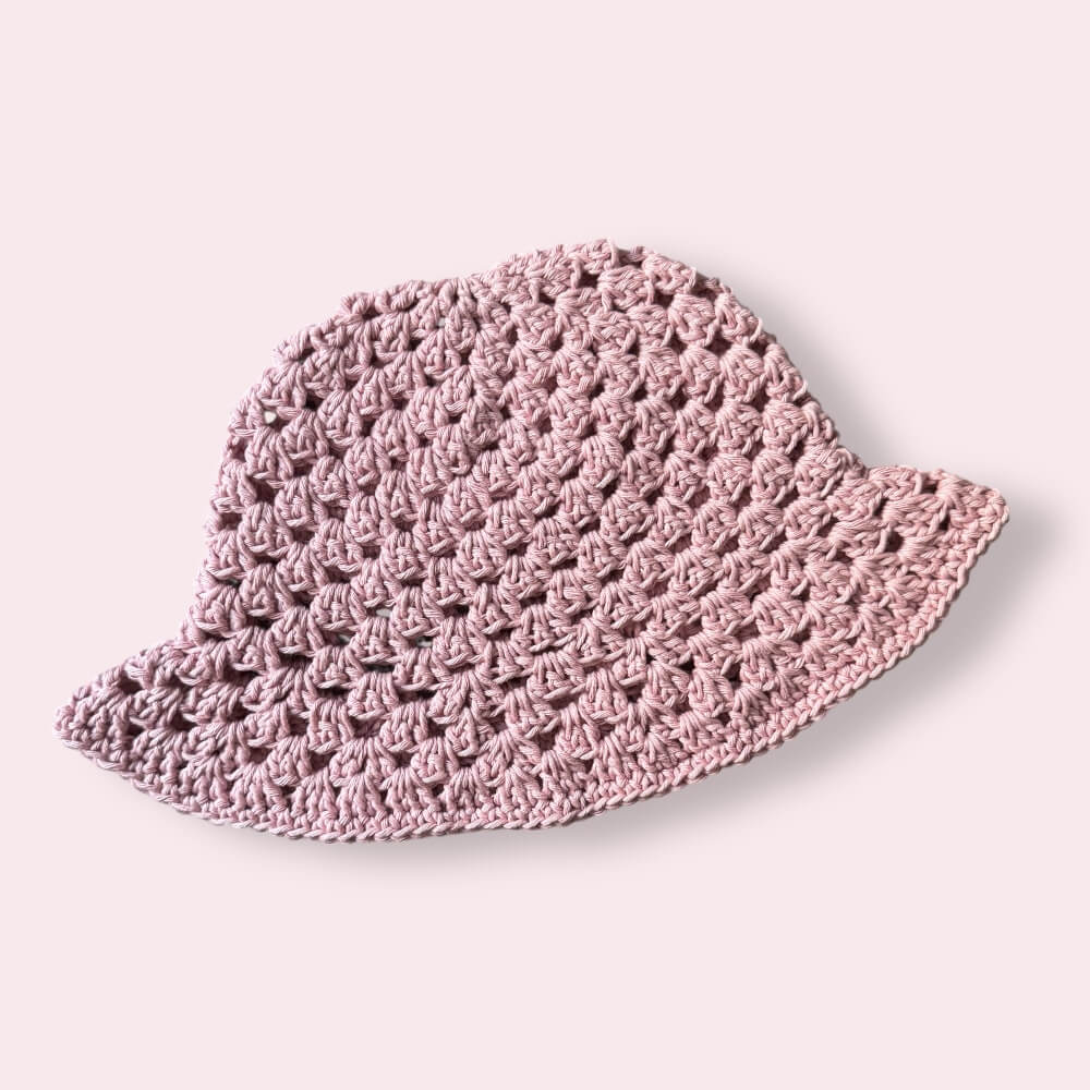 Dusty pink crochet bucket hat on plain background