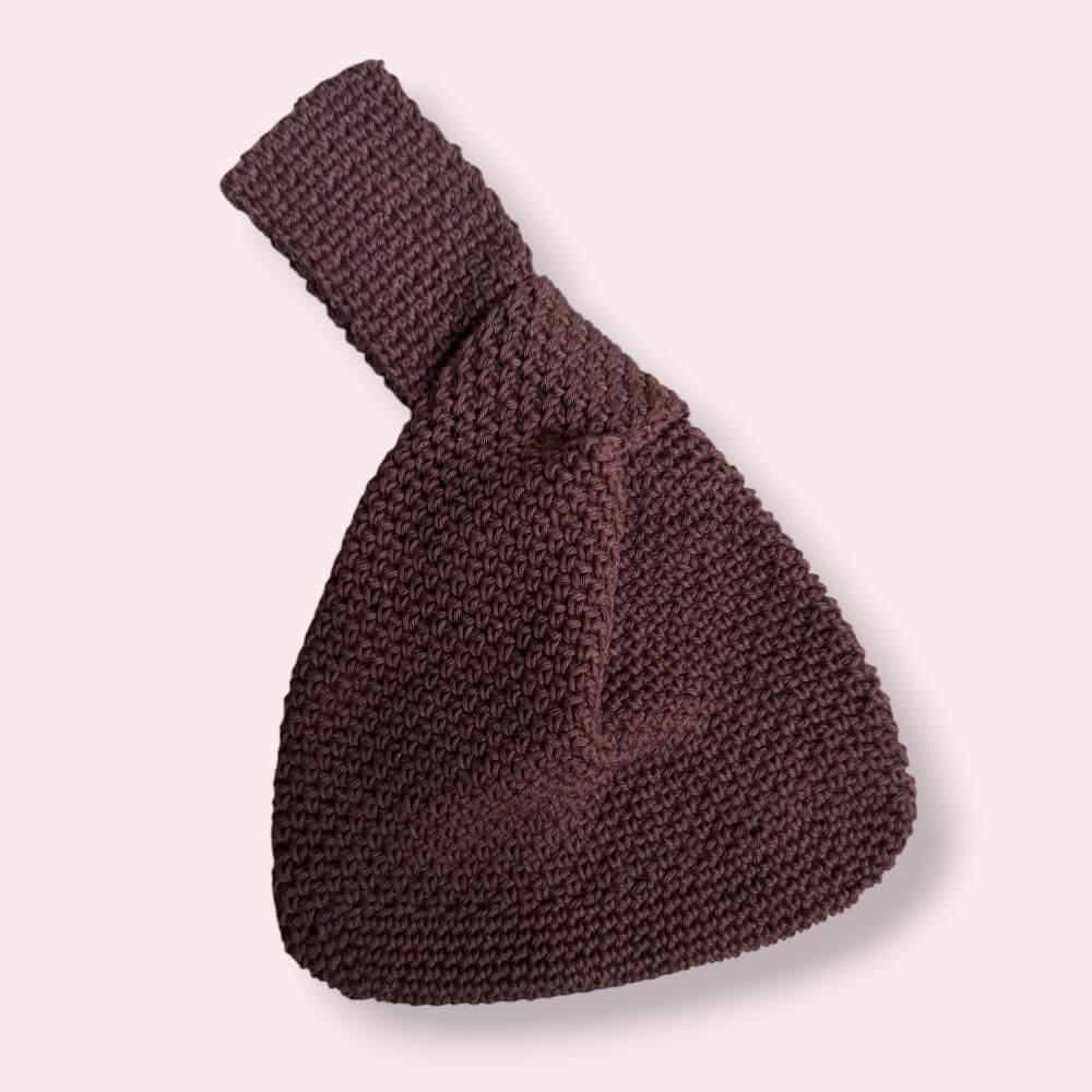 Flatlay of brown japanese knot bag on pink background