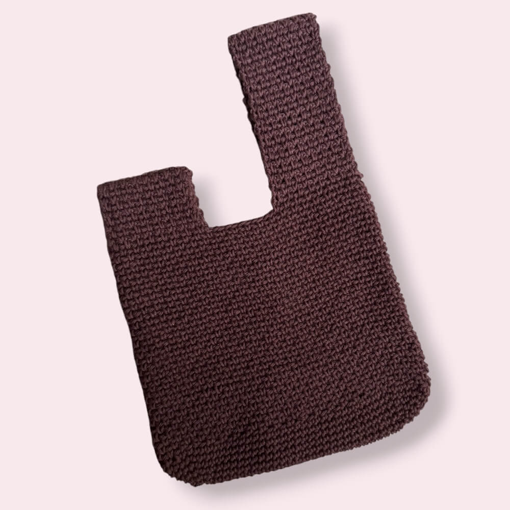 Flatlay of brown japanese knot bag on plain background