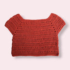 Flatlay of crochet orange tee on plain background