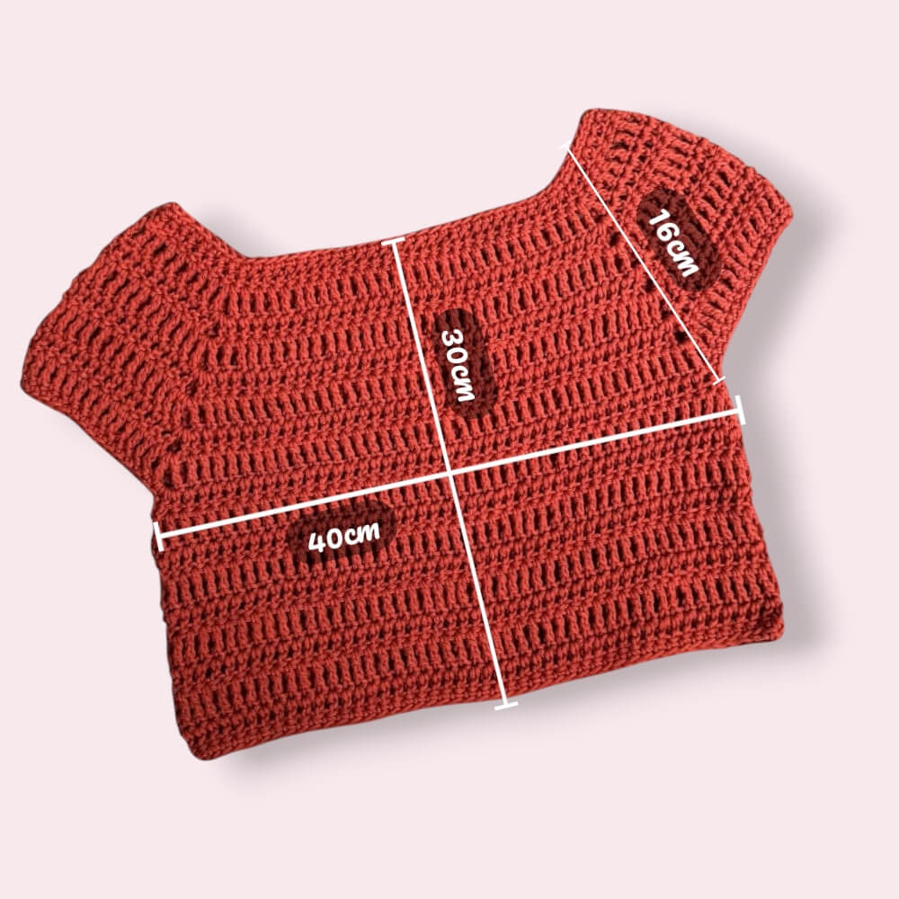 Flatlay of crochet orange tee on plain background with measurements
