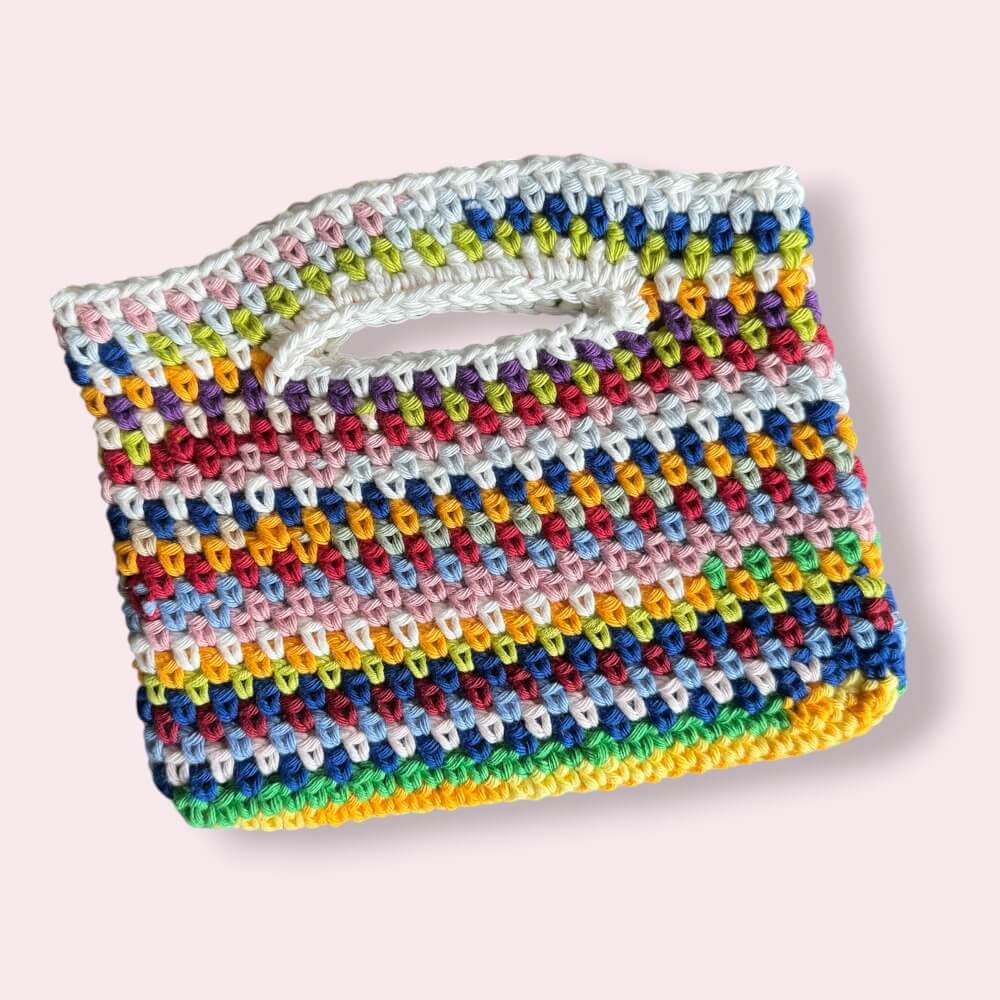 Flatlay of multicolor crochet purse on pink background