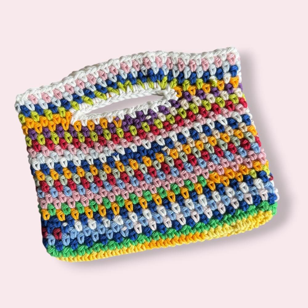 Flatlay of multicolor crochet purse on plain background