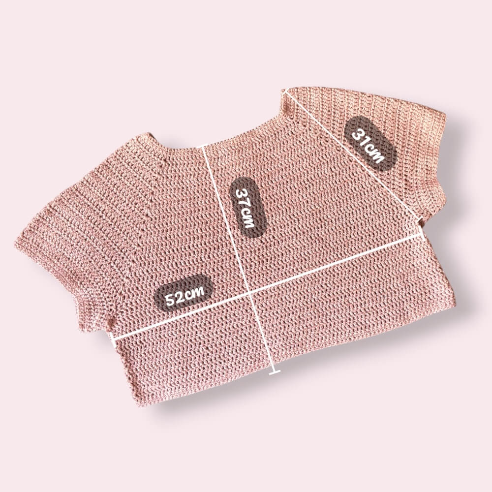 Flatlay of pink crochet tshirt on plain background with measurements