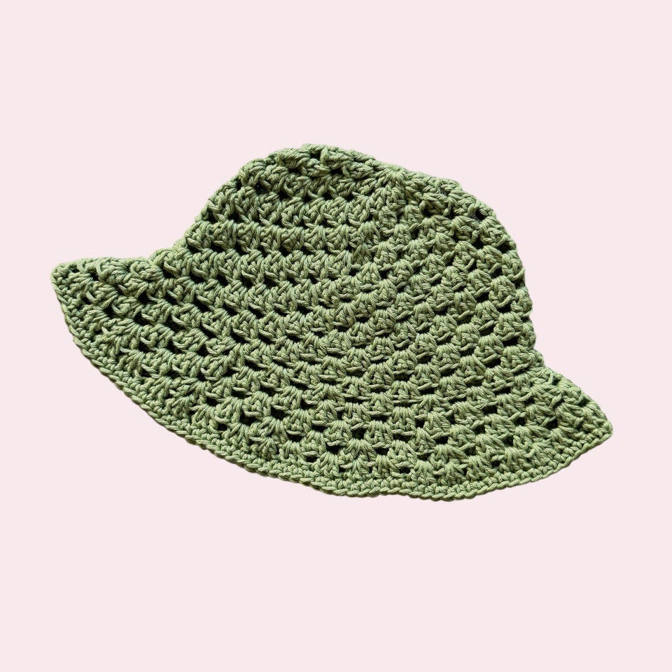 Green crochet bucket hat on a light pink background