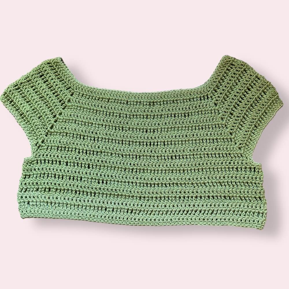Green crochet crop top on a plain background