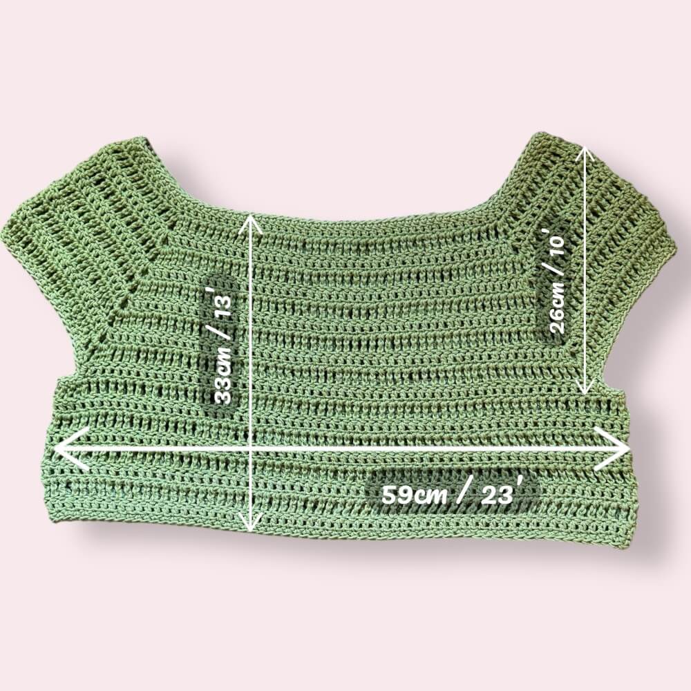 Green crochet crop top with measurements on a plain background