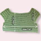Green crochet crop top with measurements on a plain background
