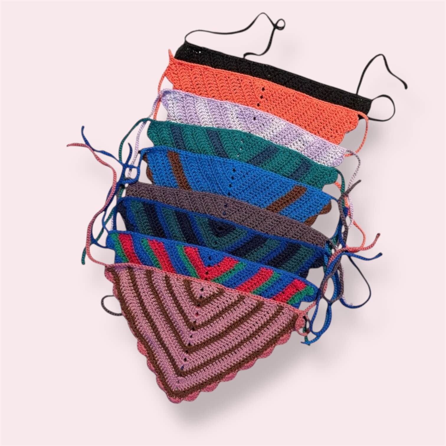 Many crochet bandanas in different colors on plain background