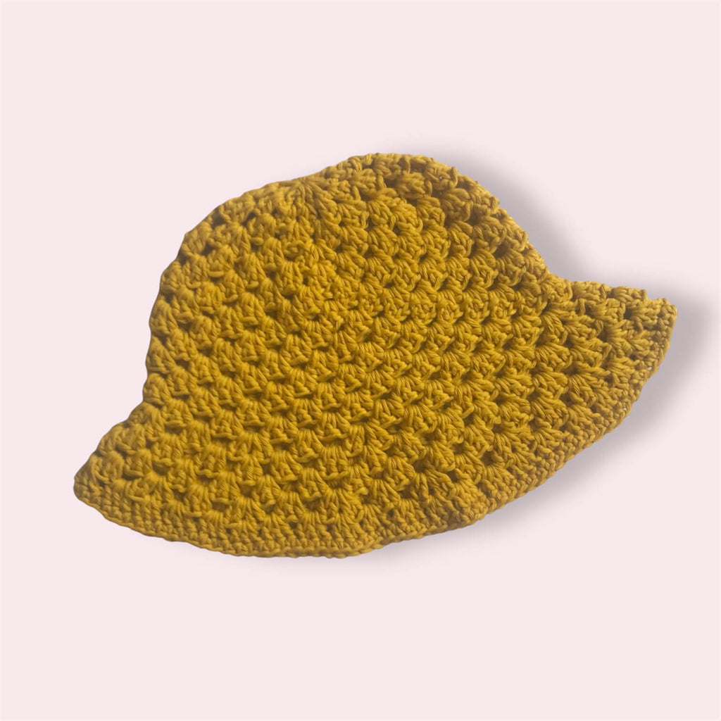 Mustard yellow crocheted bucket hat on plain background