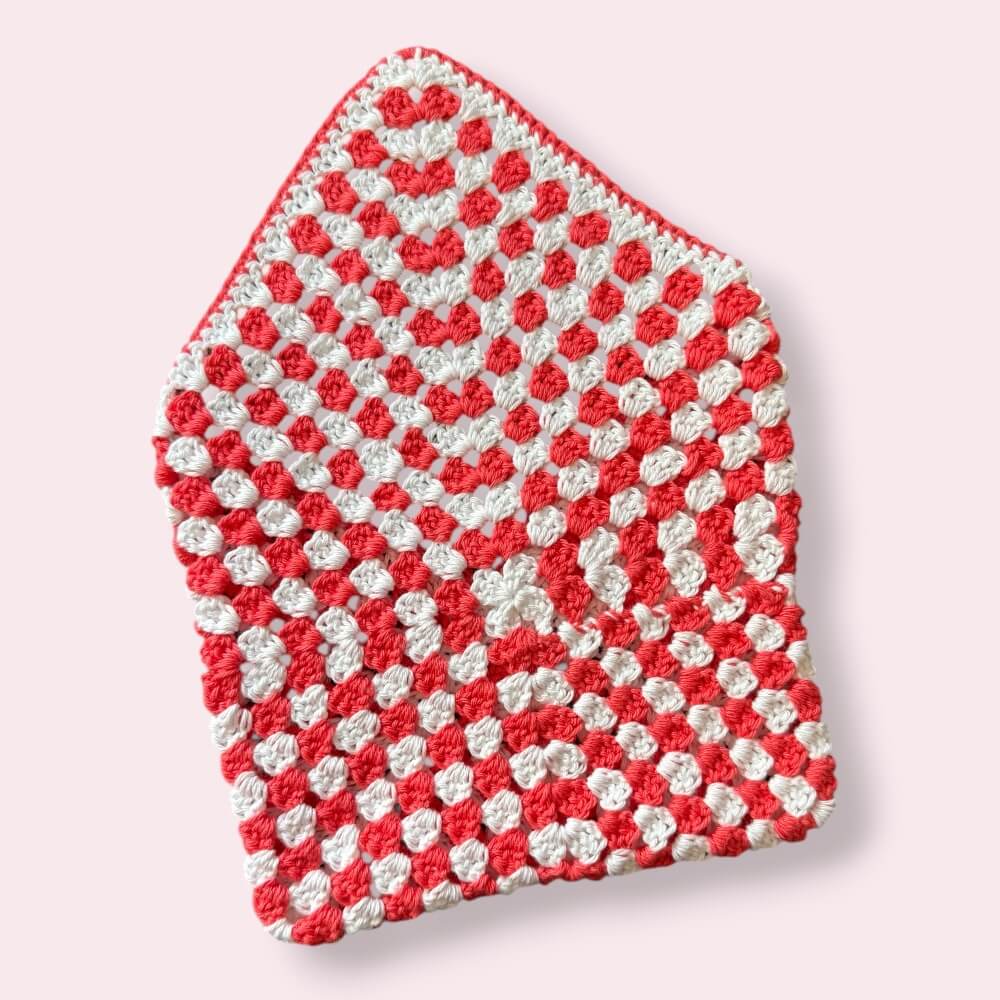 Open crocheted coral and white kindle sleeve back view on plain background