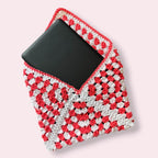 Open crocheted coral and white kindle sleeve with e-reader poking out on plain background