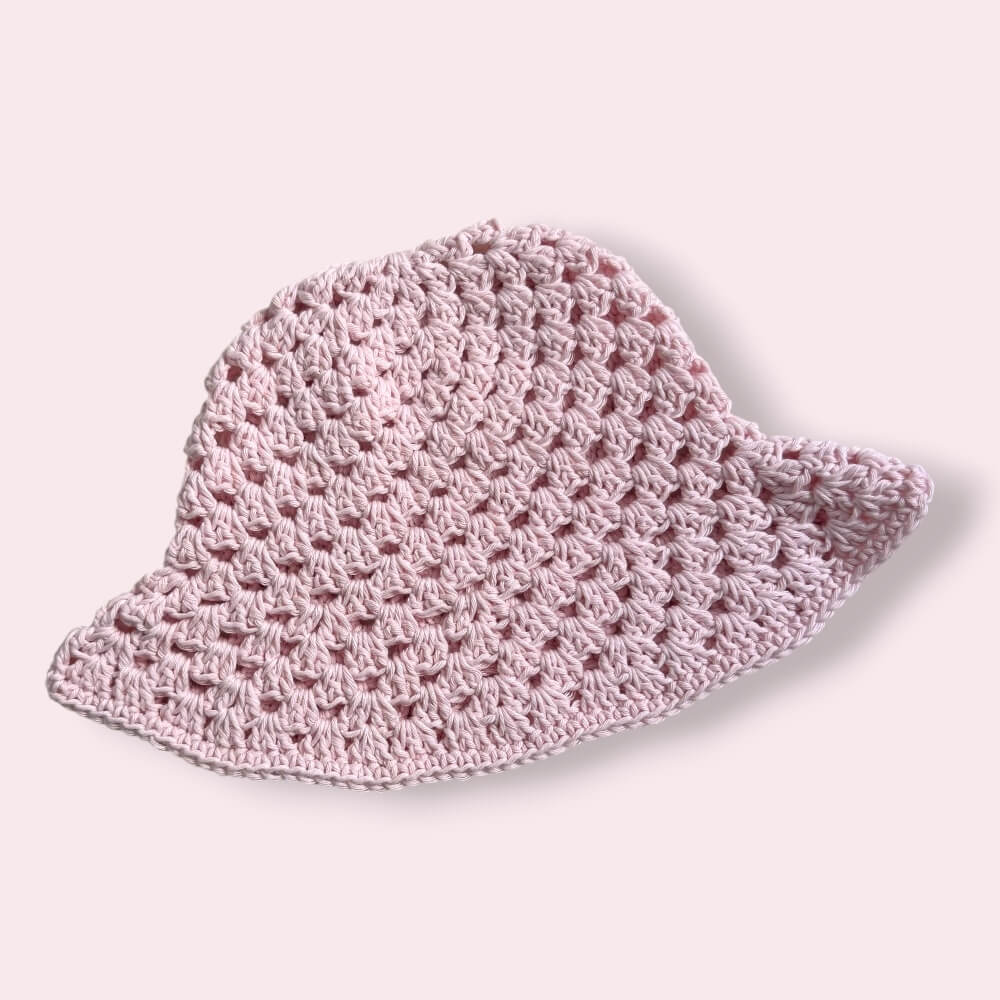 Pastel pink crochet bucket hat on plain background
