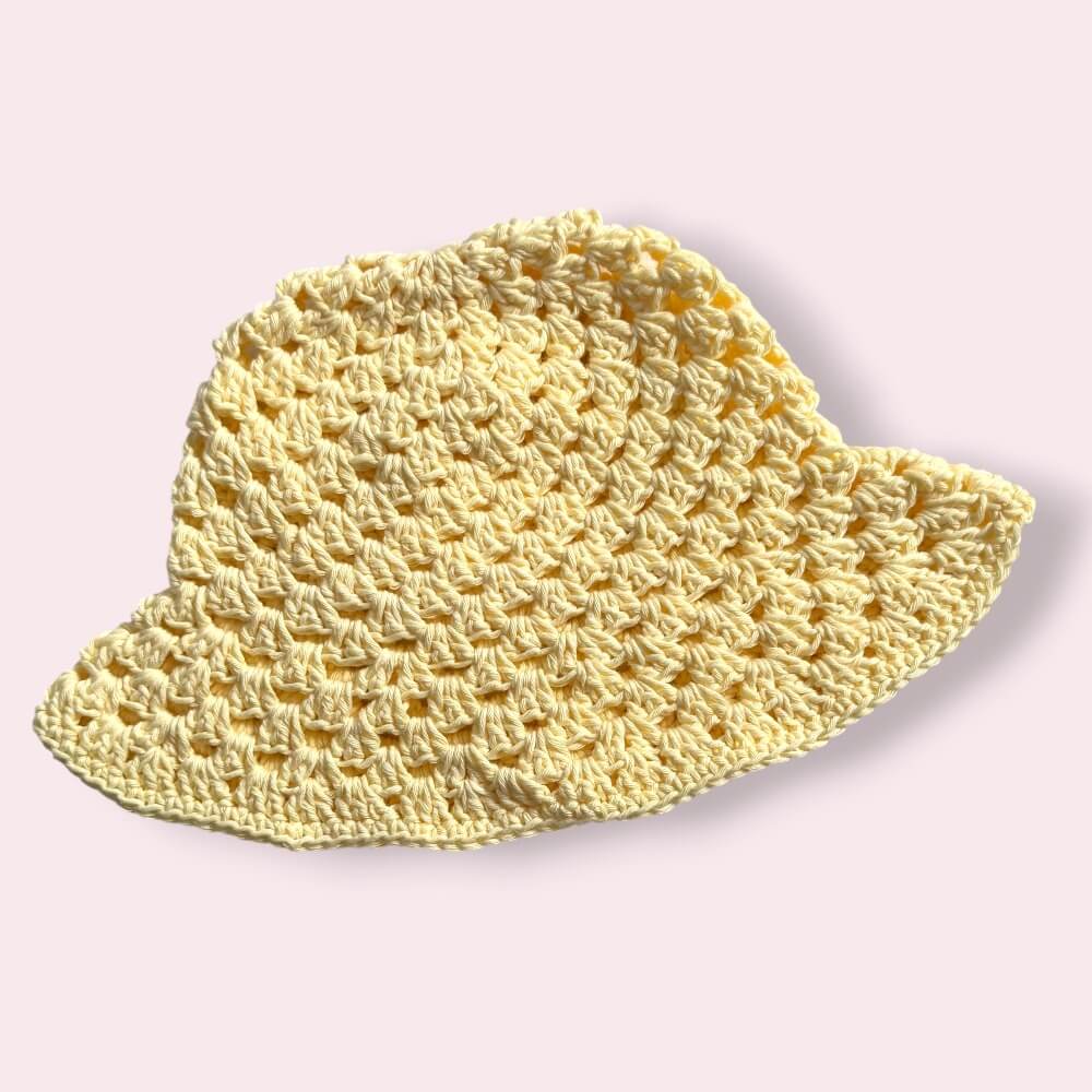 Pastel yellow crochet bucket hat on plain background