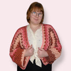 Person posing in pink crochet cardigan front view