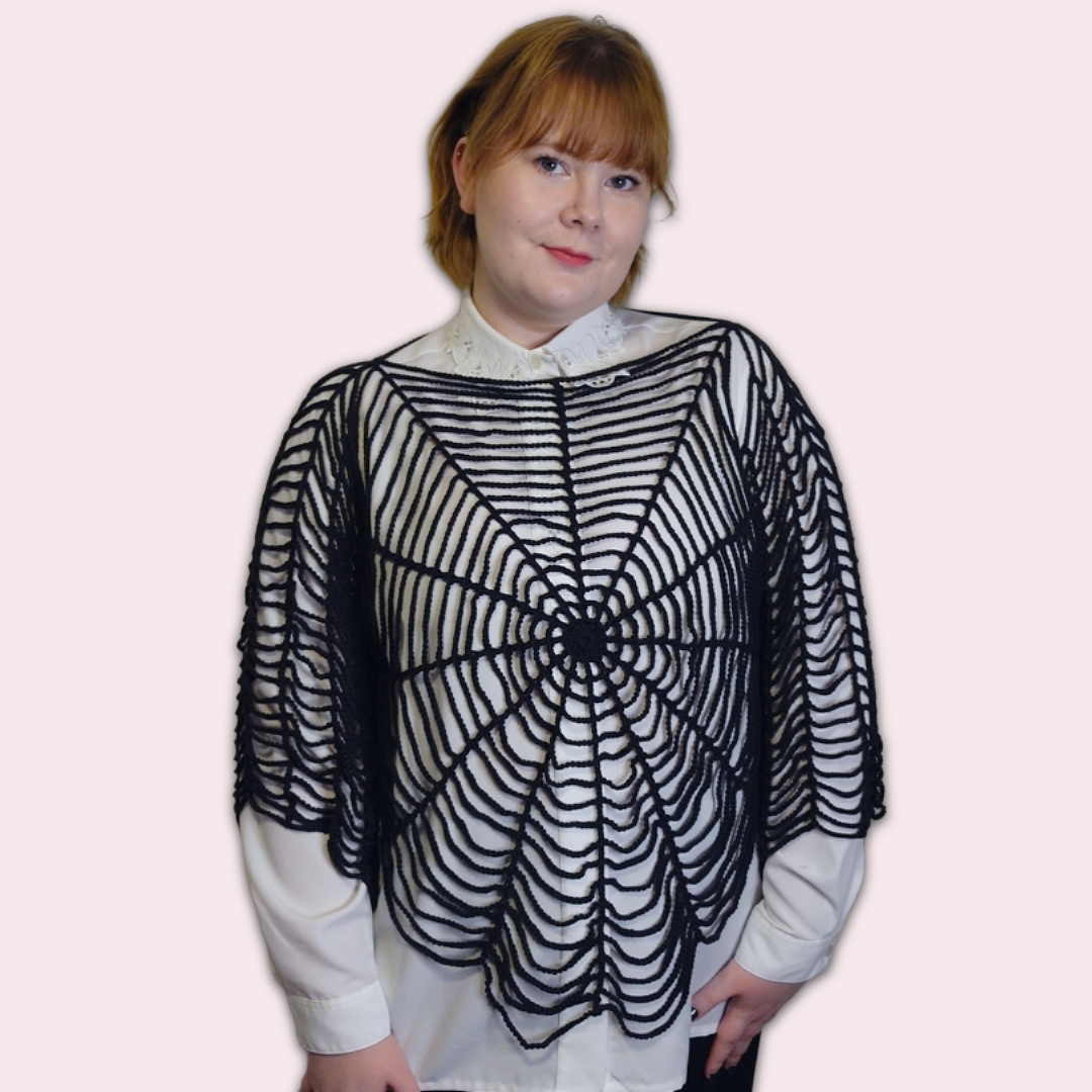 Person wearing a black spider web crochet shirt on a plain background