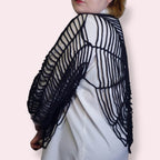 Person wearing a black spiderweb shirt side view on a plain background