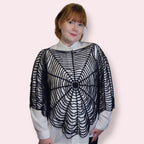 Person wearing a black spiderweb shirt with a plain background