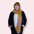 Person wearing a colorful crochet scarf on a plain background