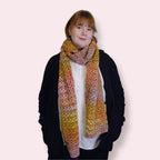 Person wearing a colorful crocheted scarf on a plain background