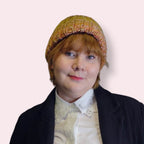 Person wearing a colorful knit beanie against a plain background 