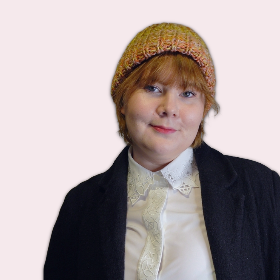 Person wearing a colorful knit beanie against a plain background 