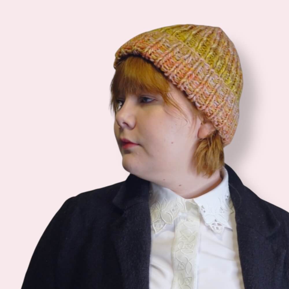 Person wearing a colorful knit beanie against a plain background Side view
