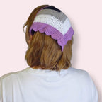 Person wearing a crochet bandana in ace pride colors on plain background 