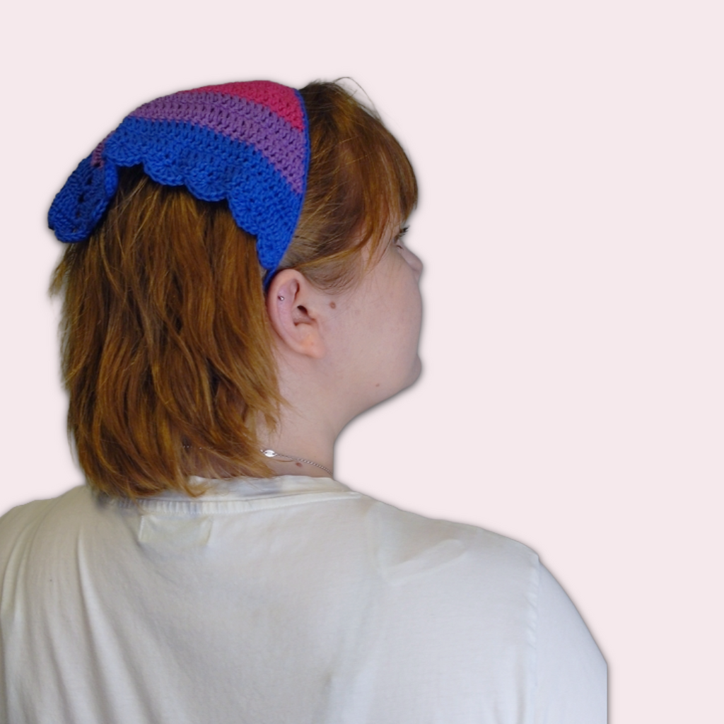 Person wearing a crochet bandana in bi pride colors on  plain background