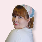 Person wearing a crochet bandana in trans pride colors on plain background