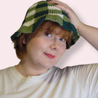 Person wearing a green and white checkered crochet bucket hat on a plain background