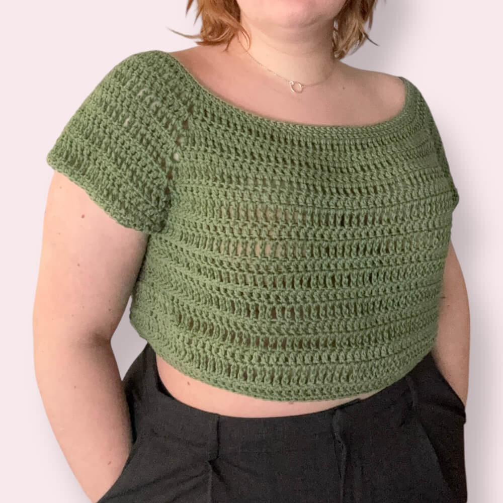 Person wearing a green crochet top against plain background