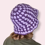 Person wearing a purple striped crochet bucket hat back view on a plain background