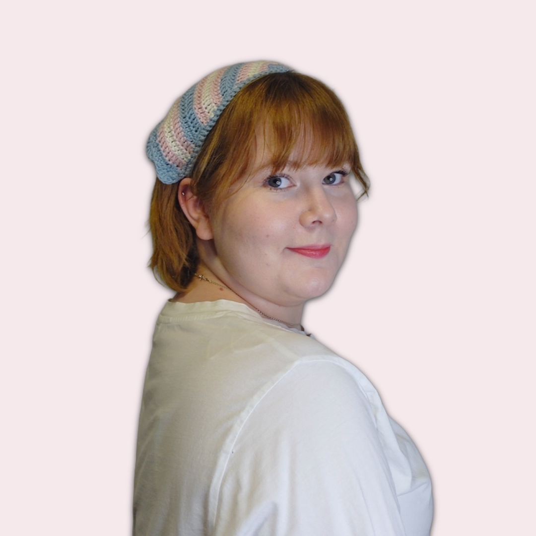 Person wearing a trans pride crocheted bandana against a pink background
