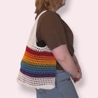 Person wearing a white and pride striped bag on a plain background