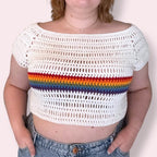 Person wearing a white crochet crop top with rainbow stripes on a plain background