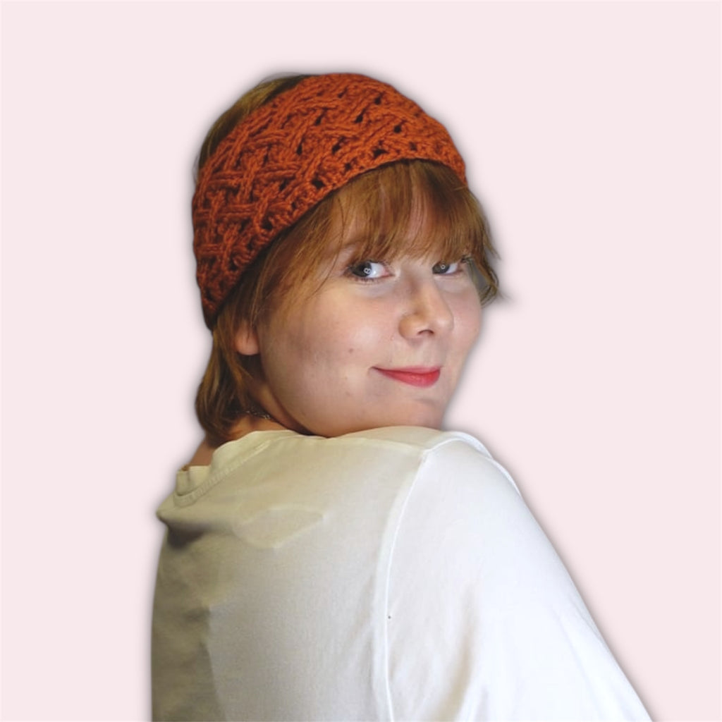 Person wearing an orange crochet headband on a plain background