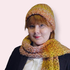 Person wearing colorful knit beanie and crochet scarf against a plain background 